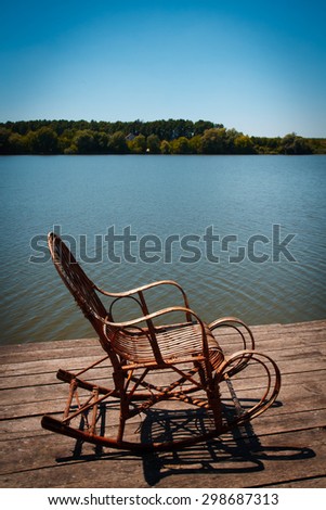 Empty chair sitting on dock by river