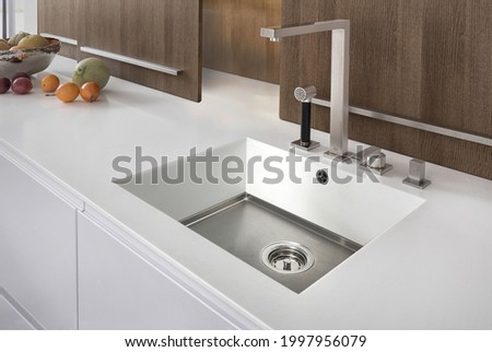 Modern kitchen with white furniture and white worktop have  undermount kitchen sink and Tap water in the kitchen. white tone 
and clean kitchen.