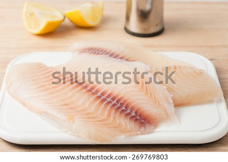 two raw fish fillets on white chopping board