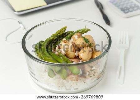 a glass container with lunch with leftovers on a desk at work