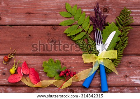 Thanksgiving table setting, top view. Cutlery on the autumn background with fallen leaves and ribbon on wooden background. Thanksgiving holidays background concept