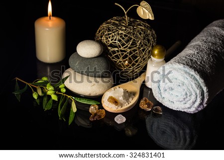 luxury SPA still life with stones, aromatic candles, olives and towel on black background