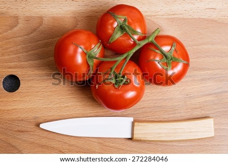 Fresh tomato and ceramic knife on the kitchen cutting board