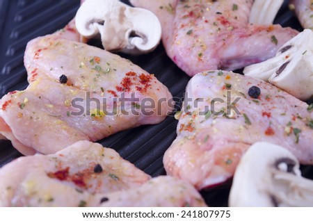 Raw chicken wings covered with spices frying on the grill
