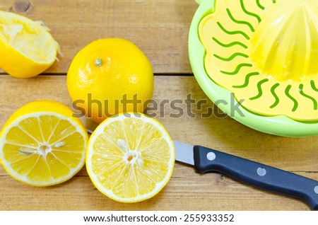 Whole, halved and squeezed lemons and a lemon squeezer on a bamboo table