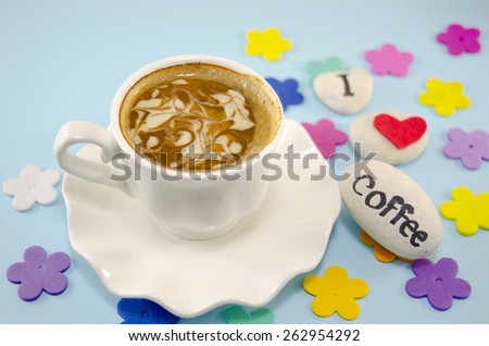 White cup of coffee with decorated foam and rocks saying \