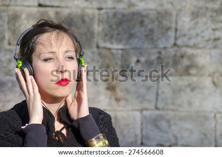 Pensive brunette listening to music on a headset outdoors