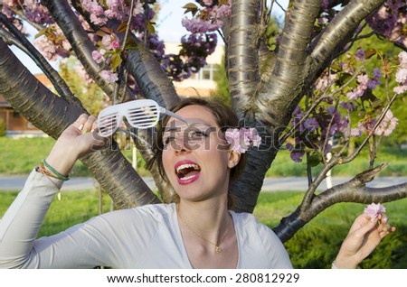 Happy girl posing with big party sunglasses outdoors with flower in her hair