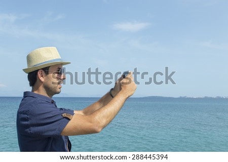 Man taking photos with his cell phone at the sea