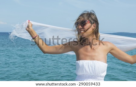 Girl vearing white dress and white scarf at sea
