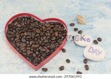 Heart shaped box filled with fried coffee beans on blue background with a \
