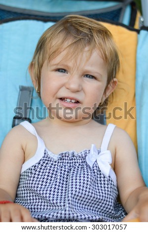 Portrait of adorable blue eyes one year old baby girl riding in baby carriage
