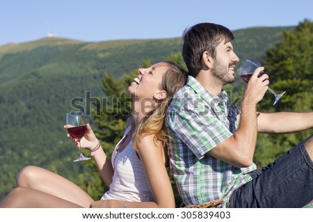 Young happy couple drinking wine on a hiking trip at the viewpoint. Couple hiking trip