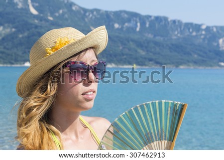 Girl with hand cooling fan at the beach.Girl with summer accessories.  Summer vacation background