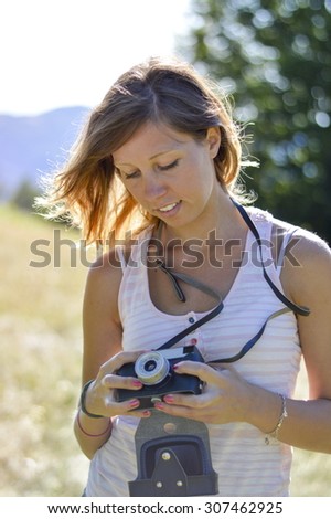 Beautiful girl portrait with an retro camera. Low depth of field with bokeh background. Hiking trip to the mountains