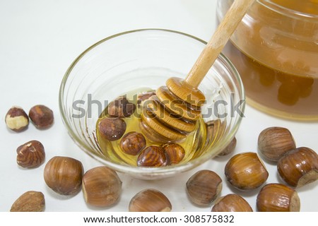 Nuts and honey in  a glass dish next to a glass with honey. Healthy dessert