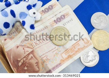 Greek old currency drachma banknotes piled on the Greek flag