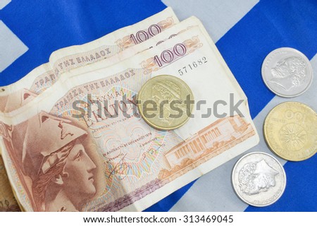 Greek old currency drachma banknotes piled on the Greek flag