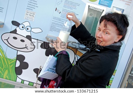 LJUBLJANA, SLOVENIA - MARCH 11: Unknown woman buys milk at milk vending machine, installed at vegetable market in Ljubljana, Slovenia, on March 11, 2013. Fresh raw milk is available 24 hours a day.