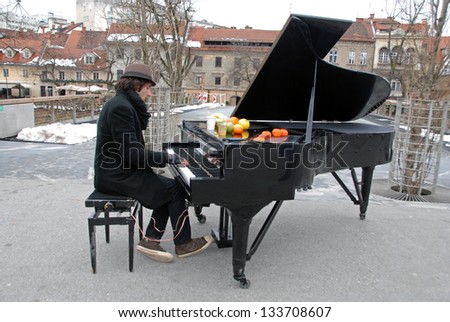 LJUBLJANA, SLOVENIA - MARCH 2: Davide Martello plays piano on Butcher\'s bridge in long winter in Ljubljana, SI, on March 2, 2013. He travels around Europe with his piano and give concerts for free.