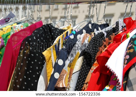 Colorful used blouses on hangers at open air second hand market