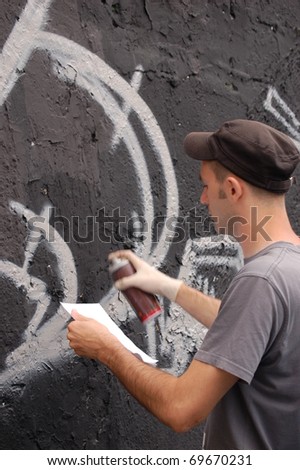 LJUBLJANA, SLOVENIA - JUNE 19: Graffiti artist paints the black wall by the plan in his hand on June 19, 2010 in Ljubljana, Slovenia. Traditional events Night in Museum take place till midnight.