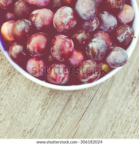 Fresh Organic Plums on Rustic Wooden Background. Retro Filter Effect. Vintage Style Harvest Background. Toned image with selective focus.