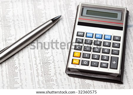 A calculator and pen on the stocks and shares page of a newspaper