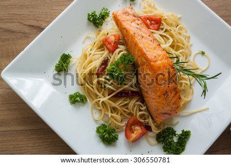 Spaghetti with salmon fillet on white dish , top view