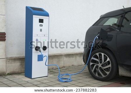 Power supply for electric car charging. Electric car charging station. Close up of the power supply plugged into an electric car being charged.