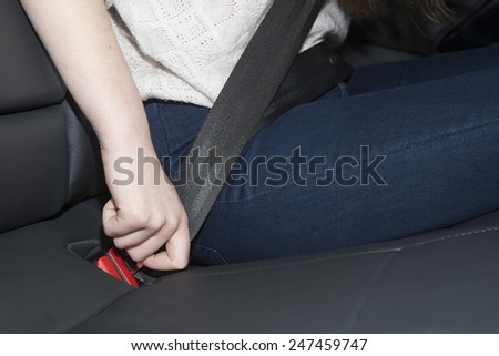 Woman sit on car seat and fasten safety belt