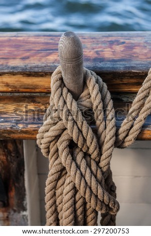 Huge rope knot tied on a wooden ship part