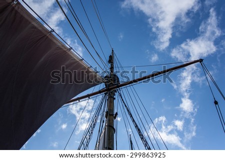 View from the bottom on the wooden ship\'s mast against vibrant blue sky