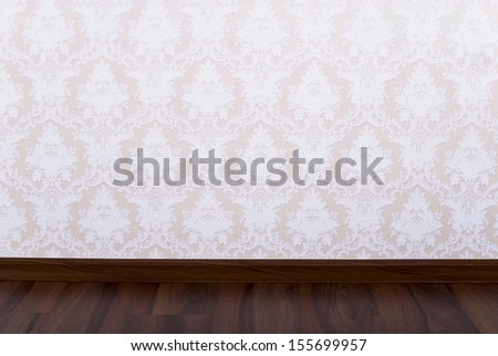 Wooden parquet floor and wallpaper on a wall close up