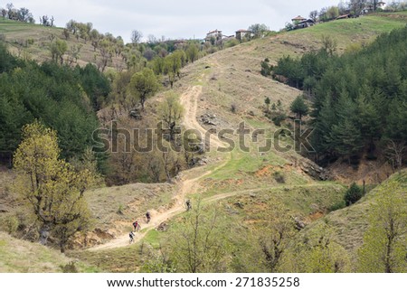 Group of mountain bikers on a steep dirt road leading to a mountain village.