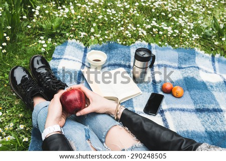 Girl with ripped jeans holding an apple during a picnic in a garden