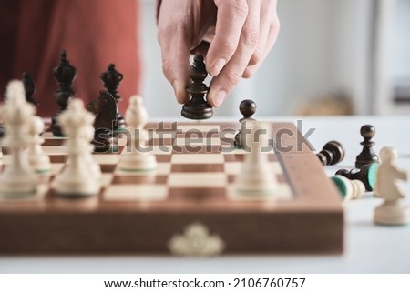 Chess game, hand moves black bishop across the chessboard. Male businessman plays chess in office. Business strategy, tactics concept. Wooden chess board, pawns, knights, rooks, bishops, queen, king
 Сток-фото © 