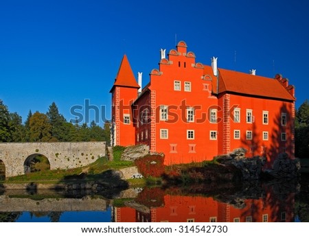 Fairy tale red castle on the lake, with dark blue sky, state castle Cervena Lhota, Czech republic