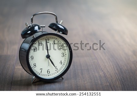 Black vintage alarm clock on a wooden floor