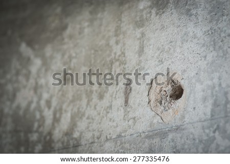 A bullet hole in the grey concrete wall