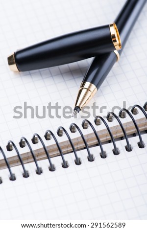 A spiral notebook with black ball pen on the white table, isolated