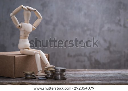 Small wooden dummy with coins over the grey concrete wall