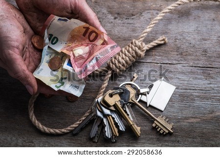 Hands holding money with hangman\'s noose, keys and money on brown wooden background