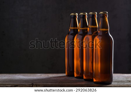Ice cold beer bottles in a row over the grey concrete wall background