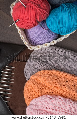 Handmade knitted hats with knitting accessories on a wooden table
