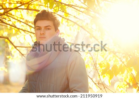 Handsome guy backlighting portrait with bokeh, outdoor in autumn park.
