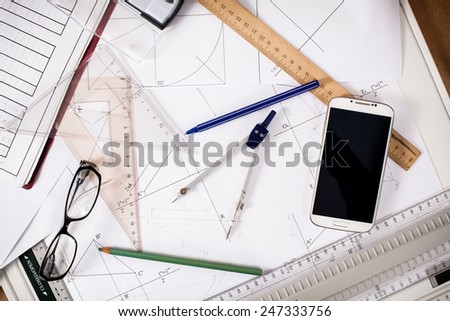 messy architect desk with paper, ruler, compasses and mobile phone