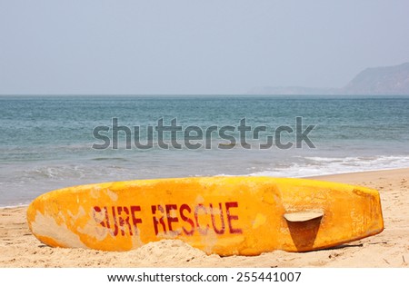 Surf rescue surfboard on the beach of an India coast city, alongside the waters edge on the seashore ready for immediate use