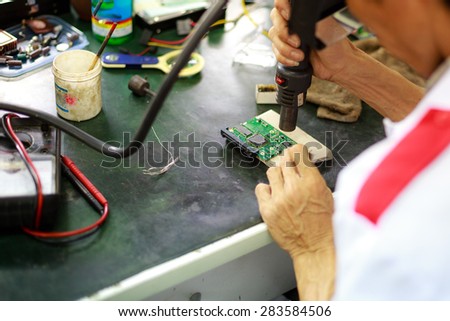 Ho Chi Minh city, Vietnam - March 17, 2015: a technician who is repairing of computer circuit board in a computer service center
