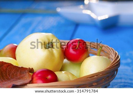 Wicker basket with fresh apples and plums